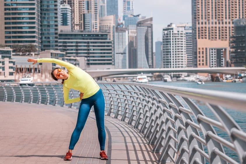 Niña joven en Dubái estirándose después de correr en la Marina.