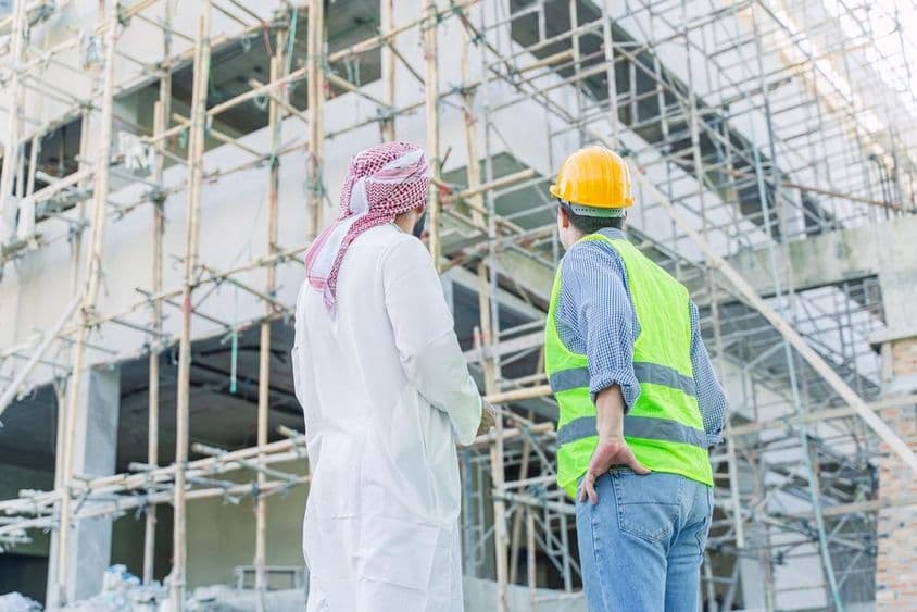 Ingeniero e inversor observando un edificio en construcción.