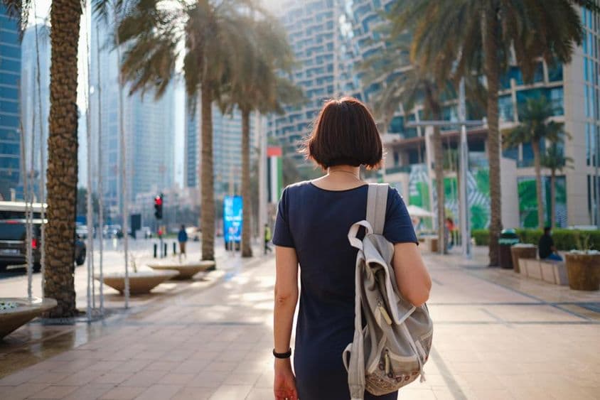 Mujer caminando en Dubái con una mochila.