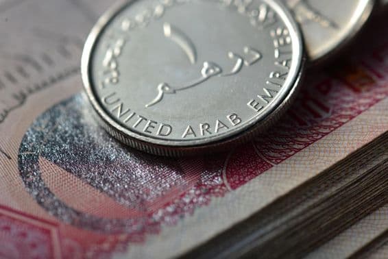 Moneda de un dirham metálica sobre una pila de billetes.