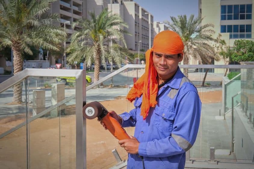 Trabajador en Dubái puliendo barandilla.
