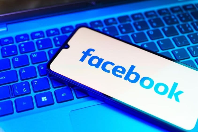 Facebook en un teléfono, teclado debajo.