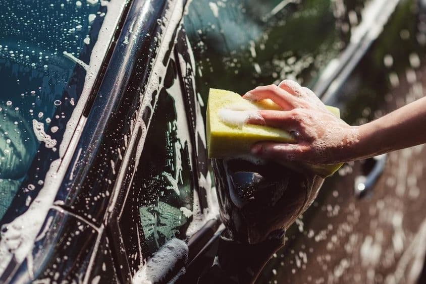 Coche siendo lavado con una esponja.