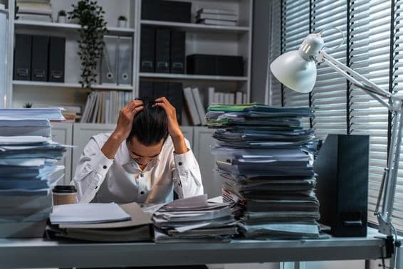 Trabajador de oficina sujetándose la cabeza debido al exceso de trabajo.