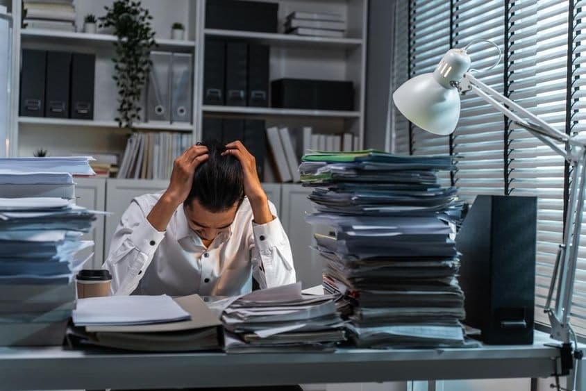 Trabajador de oficina sujetándose la cabeza debido al exceso de trabajo.