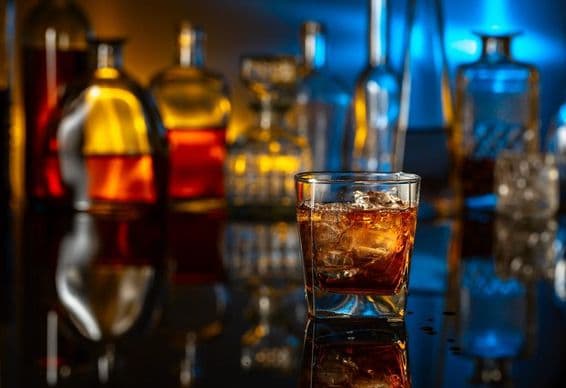 Whisky con hielo sobre una mesa negra en un bar.