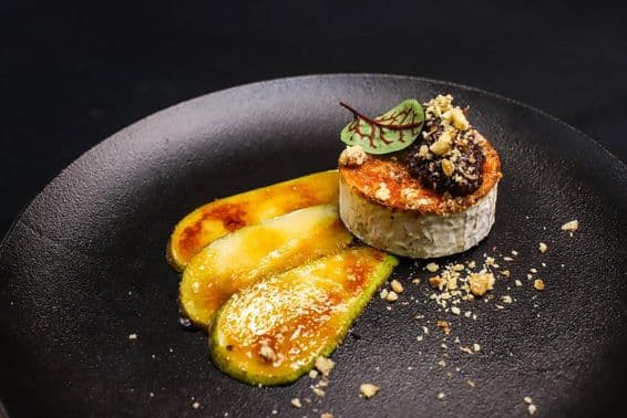 Queso de cabra asado con pera caramelizada presentado estilo alta cocina