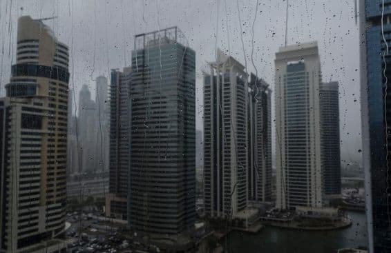 Primer plano de una ventana mojada mostrando el moderno horizonte comercial de Dubái.