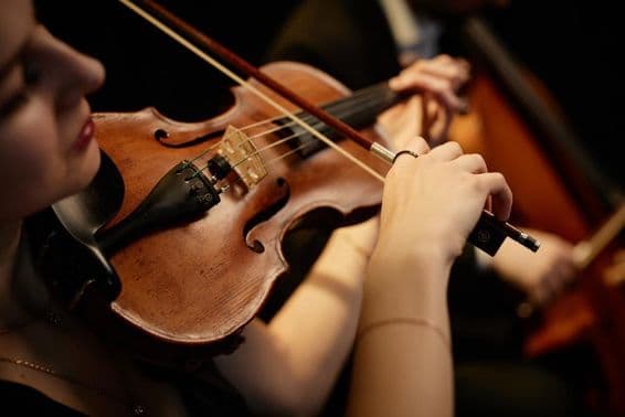 Mujer música de orquesta tocando el violín con un arco durante un concierto en el escenario.