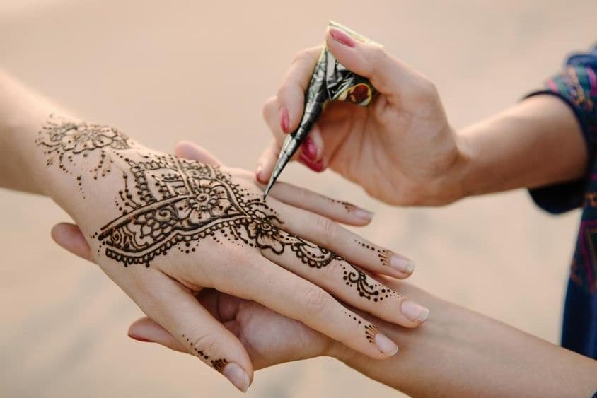 Henna siendo aplicada en la mano de una mujer.