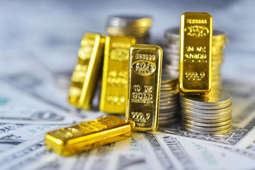 Oro de inversión 999.9 de pureza, sobre papel y monedas de dólar.