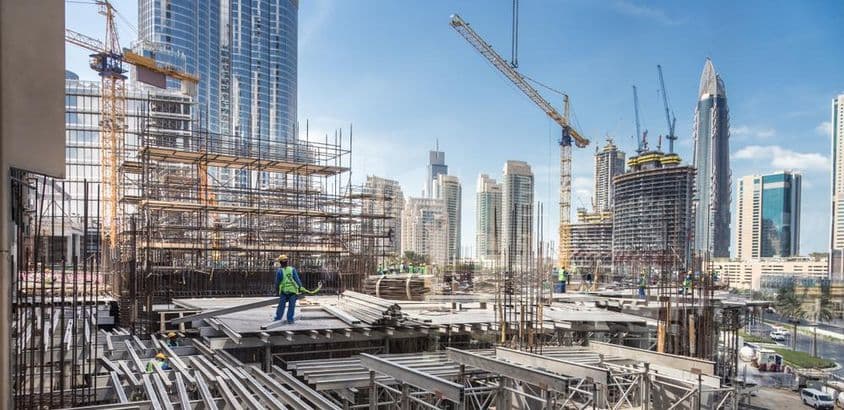 Construcción en Dubái, un trabajador apilando tablones de madera.