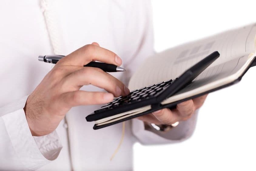 Empresario árabe sosteniendo una calculadora.