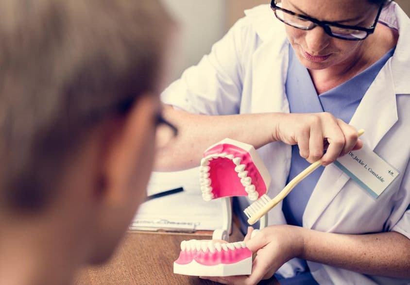 Dentista en Dubai demostrando cepillado de dientes.