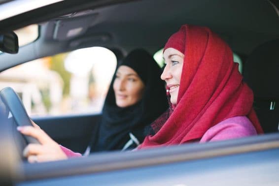 Mujer musulmana conduciendo un coche, transportando a otra mujer musulmana.