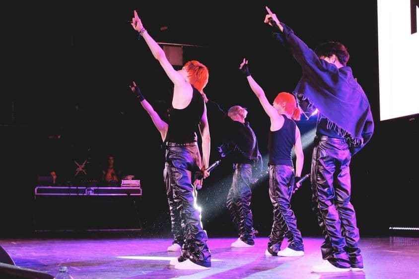 Banda de K-Pop bailando en el escenario.