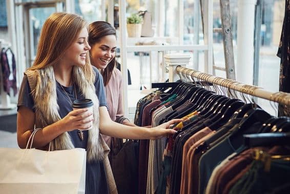 Mujeres riendo y tomando café en una boutique.