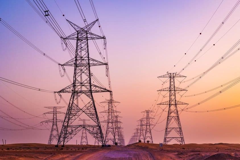 Torre de alta tensión con líneas de transmisión de energía contra un cielo colorido en el desierto de Al Qudra, Dubai, Emiratos Árabes Unidos.