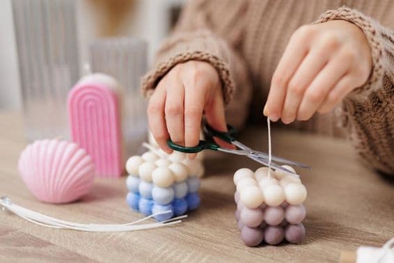 Vela esferoide sobre una mesa, una niña corta la mecha.