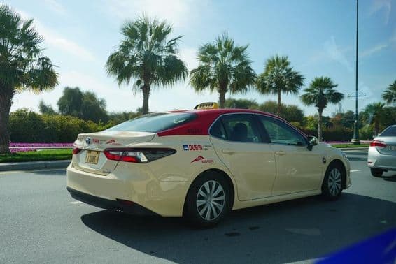 Taxi de Dubai con techo rojo conduciendo por la carretera.