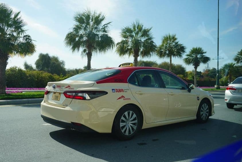 Taxi de Dubai con techo rojo conduciendo por la carretera.