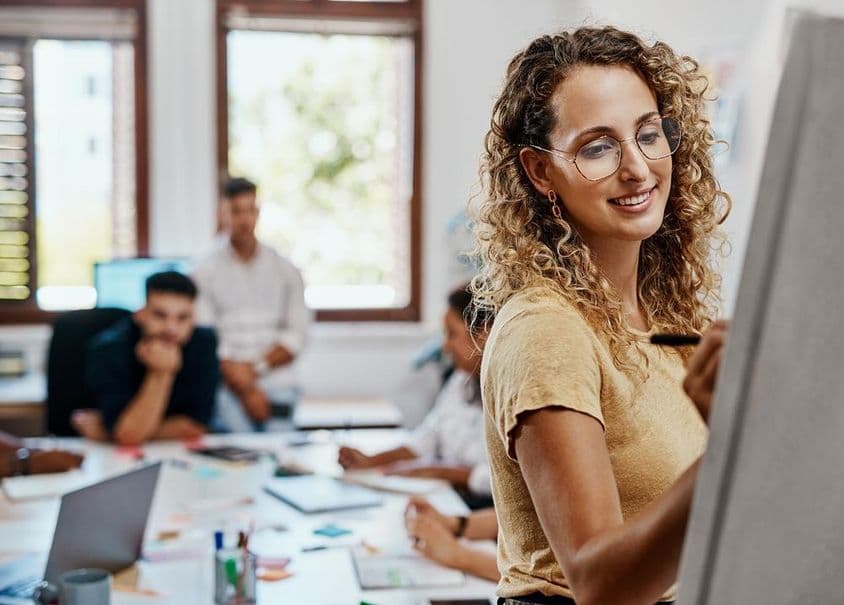 Reunión de coaching y presentación con una diseñadora en un lugar de trabajo creativo para el desarrollo de habilidades.