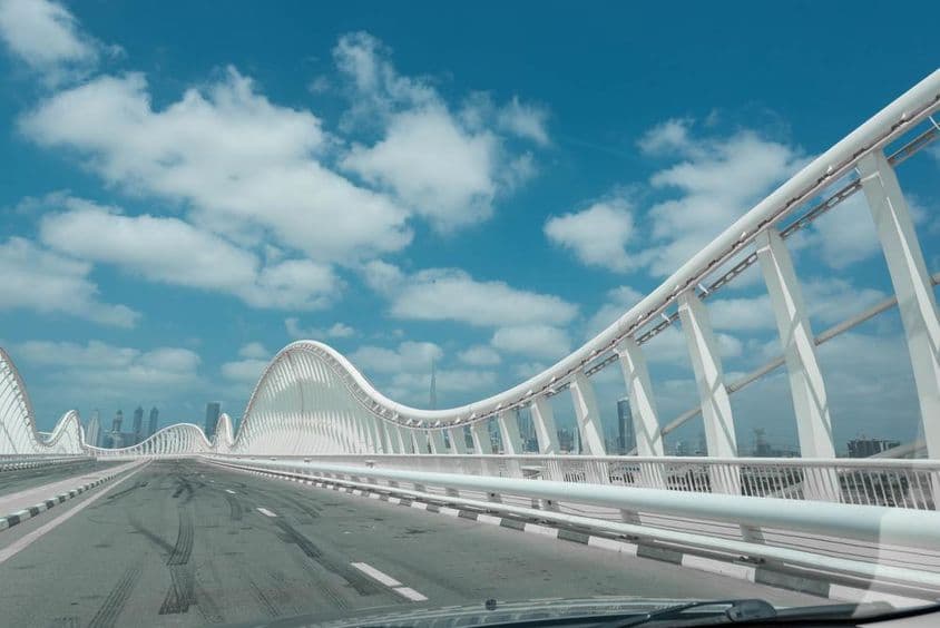 Puente moderno blanco con cielo azul y nubes al fondo.