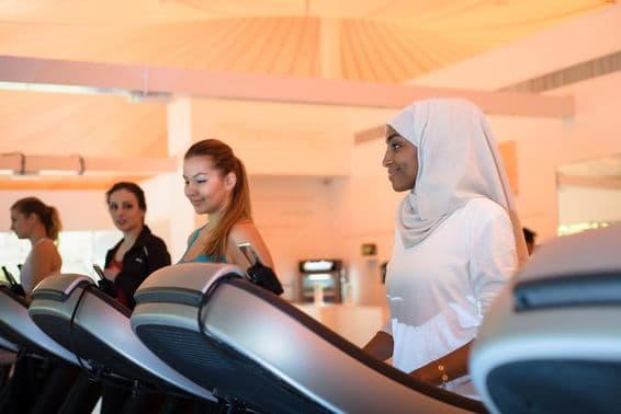 Grupo de mujeres usando la caminadora en el gimnasio.