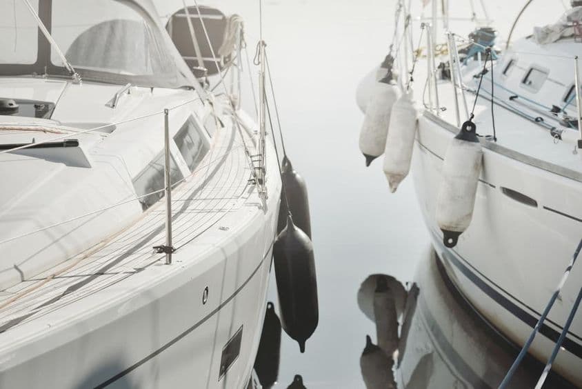 Velero blanco y moderno atracado en un puerto deportivo.
