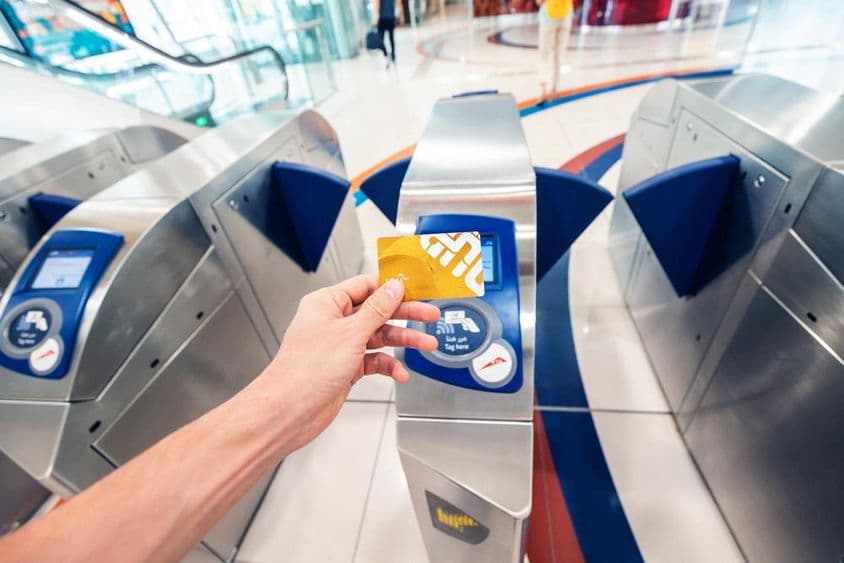 Un pasajero masculino usa una tarjeta NOL dorada en el metro de Dubái para pasar por un torniquete y viajar en el primer vagón.