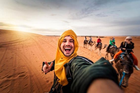 Turista feliz disfrutando de un paseo en camello por el desierto.
