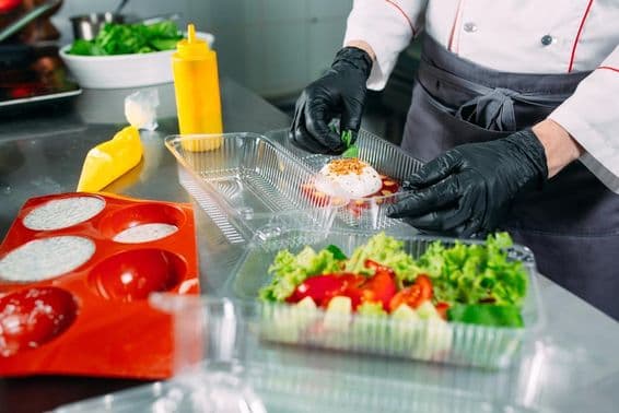 El chef prepara comida en el restaurante y la empaca en recipientes desechables.