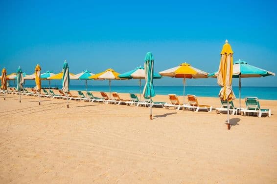 Playa pública de Dubái, costa arenosa, tumbonas y mar azul.