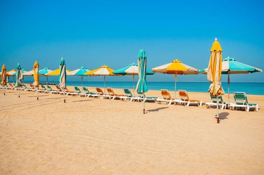 Playa pública de Dubái, costa arenosa, tumbonas y mar azul.