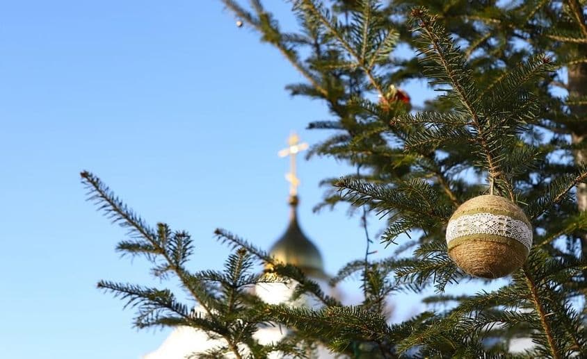 Rama de árbol de Navidad con adornos, con una cruz ortodoxa al fondo