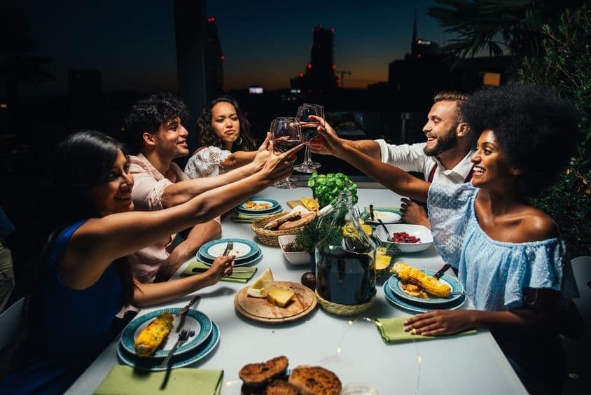 Grupo de amigos disfrutando de una comida y celebrando en un hermoso balcón de ático.