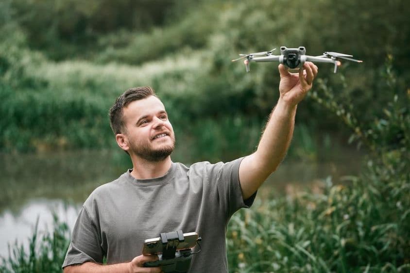 Instructor de drones con dron en mano durante clase al aire libre.