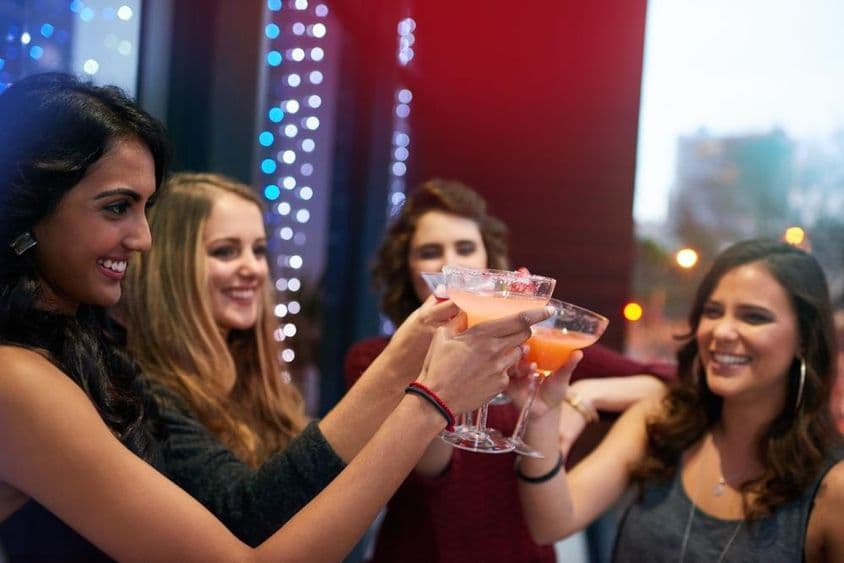 Chicas brindando con bebidas en un bar de cócteles.