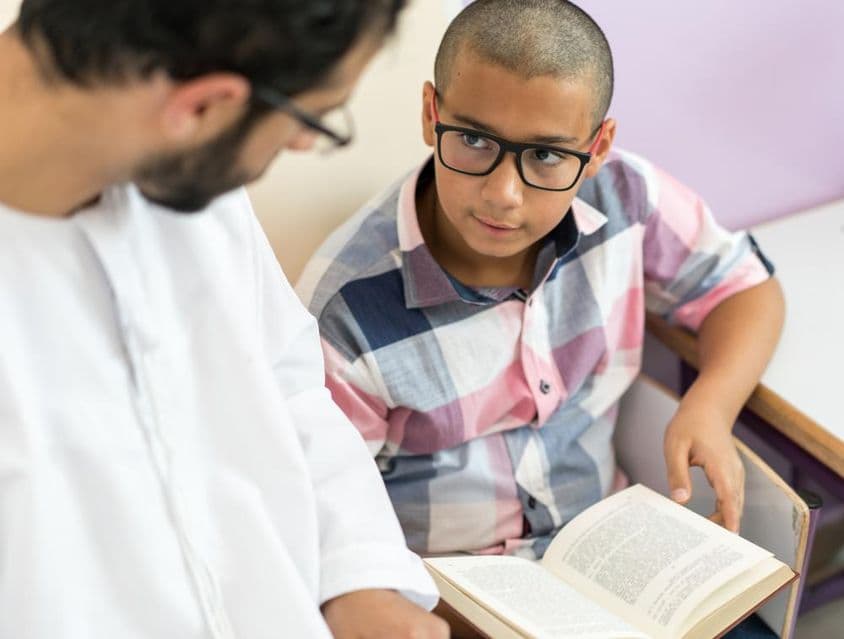 Joven maestro árabe estudiando con un escolar.