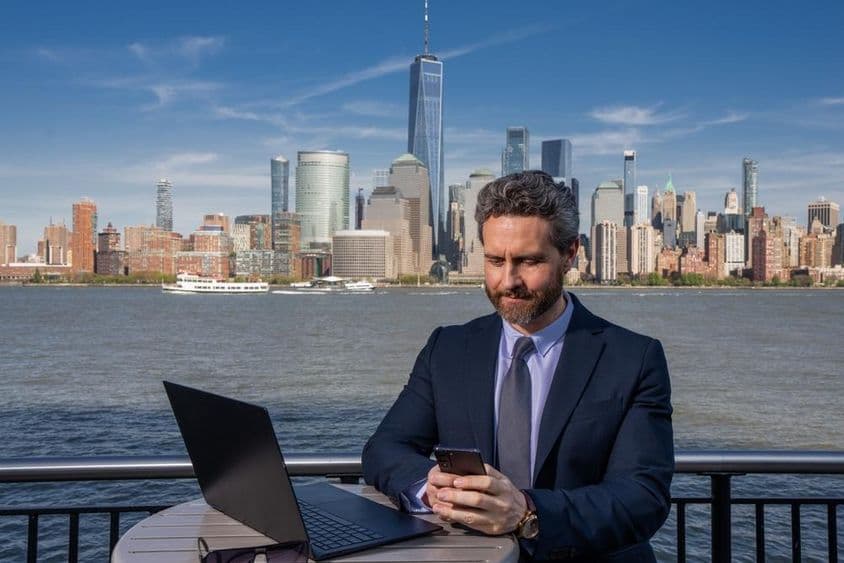 Empresario usando una computadora portátil al aire libre, trabajando a distancia.