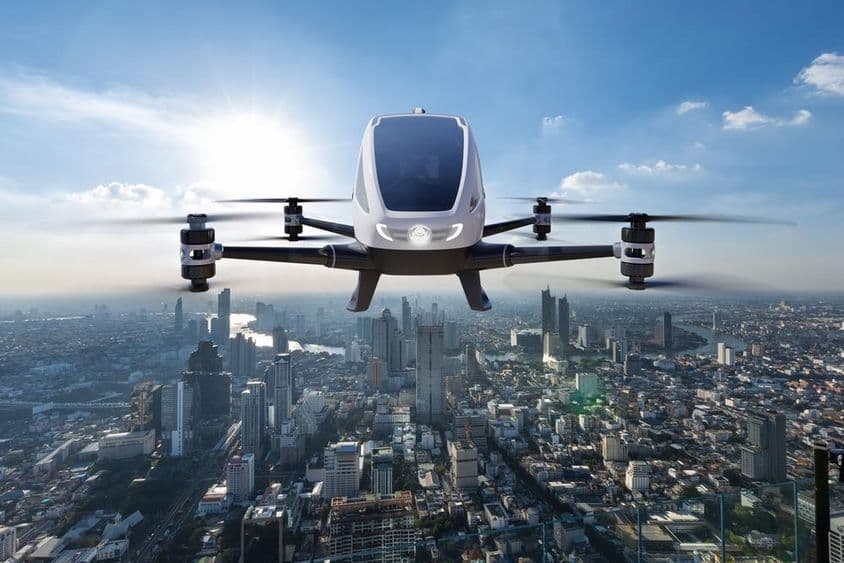Vehículo aéreo autónomo volando contra un telón de fondo urbano.