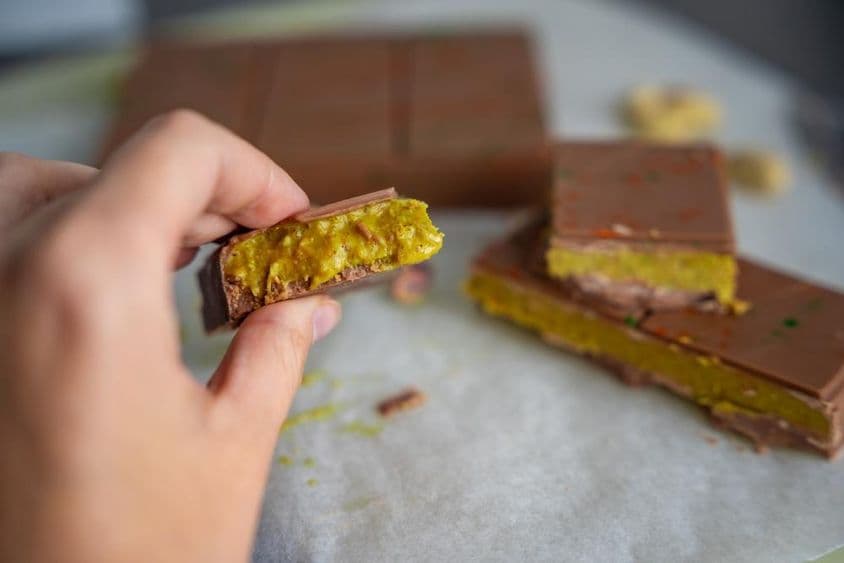 Pieza de chocolate de Dubái con pistacho y masa kataifi en la mano de una mujer.
