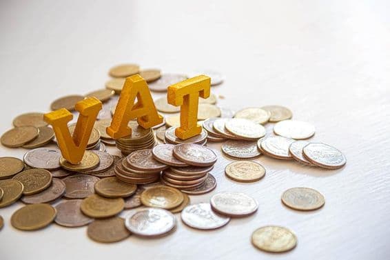 Monedas en una mesa con las letras "Impuesto" arriba.