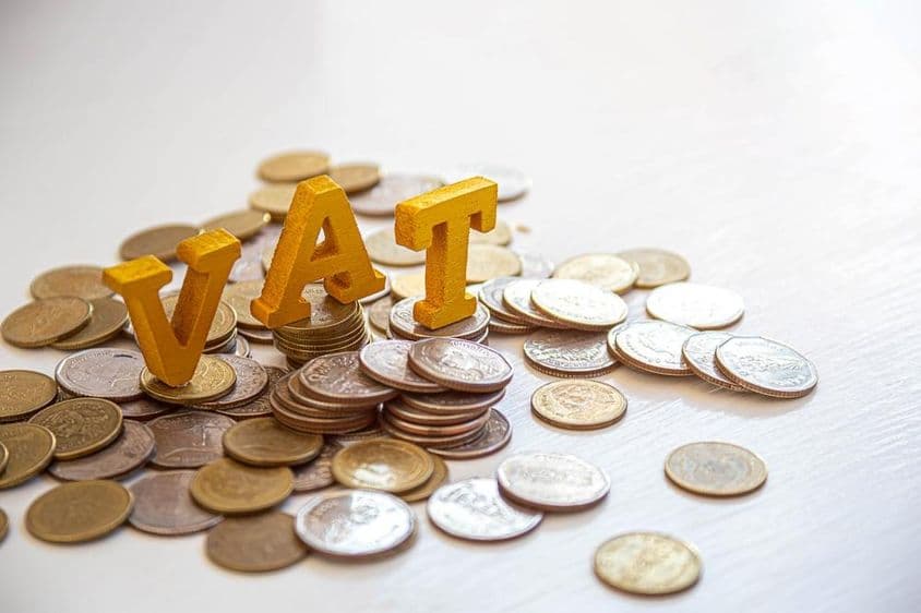 Monedas en una mesa con las letras "Impuesto" arriba.