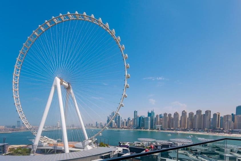 Rueda de la fortuna Ain Dubai con rascacielos y mar al fondo.