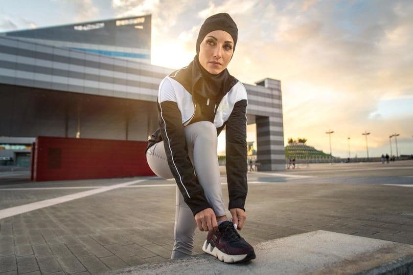 Mujer musulmana haciendo ejercicio de correr en el centro de la ciudad.