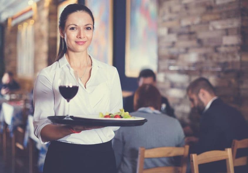 Camarera feliz sosteniendo una bandeja para los clientes del restaurante.