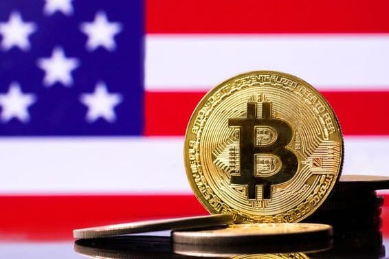 Moneda de metal Bitcoin dorada con la bandera de EE.UU. de fondo.