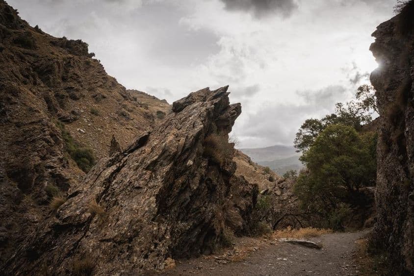 Roca sobresaliente en un camino de montaña en un día nublado.