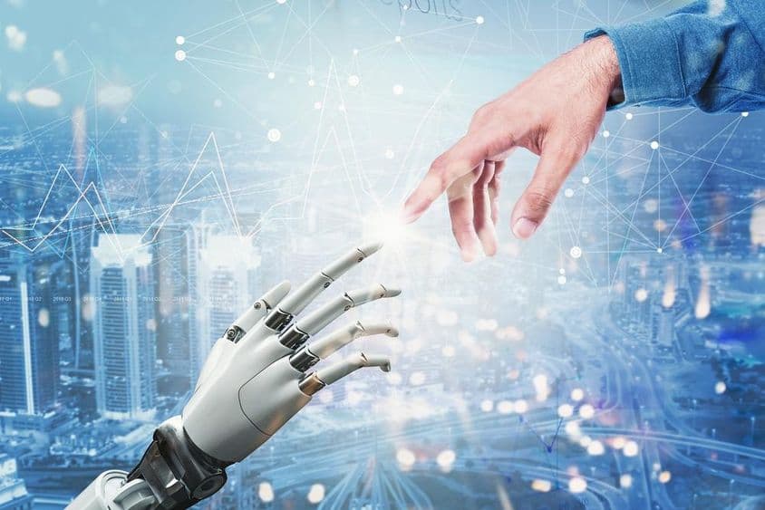 Mano robótica 3D encontrándose con mano humana sobre un paisaje urbano futurista.